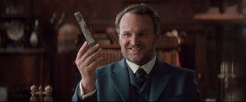 Movie still from “Winchester” (2018), directed by Michael Spierig – A man in a suit and tie holding a cell phone; Close Up shot, Low angle