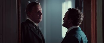 Movie still from “Winchester” (2018), directed by Michael Spierig – Two men standing next to each other in front of a window; Medium shot, Over the shoulder angle