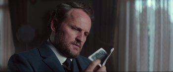 Movie still from “Winchester” (2018), directed by Michael Spierig – A person wearing a suit and tie; Close Up shot, Over the shoulder angle