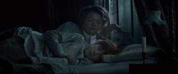 Movie still from “Winchester” (2018), directed by Michael Spierig – A woman and a child laying in a bed together; Medium shot, High angle