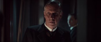 Movie still from “Winchester” (2018), directed by Michael Spierig – A person wearing a suit and tie; Close Up shot, Low angle