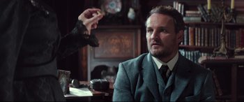 Movie still from “Winchester” (2018), directed by Michael Spierig – A man sitting at a table with a cigarette in his hand; Close Up shot, Over the shoulder angle