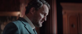 Movie still from “Winchester” (2018), directed by Michael Spierig – A person wearing a suit and tie; Close Up shot, Low angle