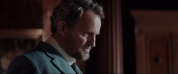 Movie still from “Winchester” (2018), directed by Michael Spierig – A person wearing a suit and tie; Close Up shot, Low angle