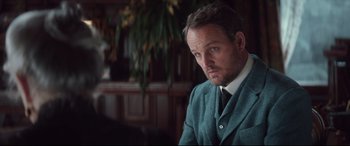 Movie still from “Winchester” (2018), directed by Michael Spierig – A person wearing a suit and tie; Close Up shot, Over the shoulder angle