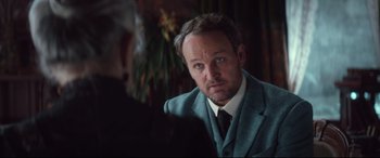 Movie still from “Winchester” (2018), directed by Michael Spierig – A person wearing a suit and tie; Close Up shot, Over the shoulder angle