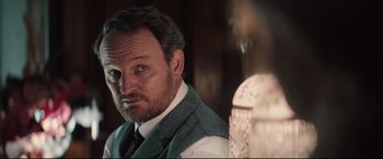 Movie still from “Winchester” (2018), directed by Michael Spierig – A person wearing a suit and tie; Close Up shot, Over the shoulder angle