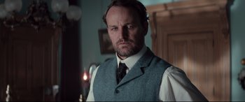 Movie still from “Winchester” (2018), directed by Michael Spierig – A person wearing a vest and tie; Close Up shot, Low angle