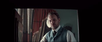 Movie still from “Winchester” (2018), directed by Michael Spierig – A man wearing a suit and tie standing in front of a mirror; Close Up shot, Low angle