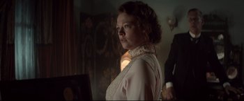 Movie still from “Winchester” (2018), directed by Michael Spierig – A woman standing in front of a wall with a lamp; Medium shot, Over the shoulder angle