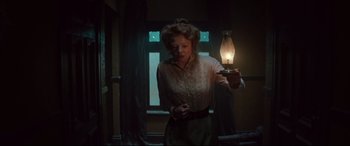 Movie still from “Winchester” (2018), directed by Michael Spierig – A woman holding a lamp in a dark room; Medium shot, Low angle