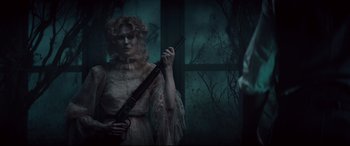 Movie still from “Winchester” (2018), directed by Michael Spierig – A woman holding a rifle in a dark room; Medium shot, Over the shoulder angle