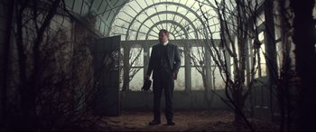 Movie still from “Winchester” (2018), directed by Michael Spierig – A man in a suit standing in front of an arched window; Wide shot, Low angle