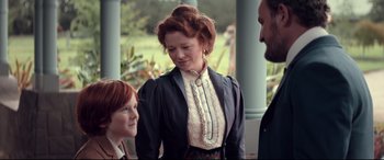 Movie still from “Winchester” (2018), directed by Michael Spierig – A woman with red hair standing next to two other people; Medium shot, Over the shoulder angle