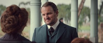 Movie still from “Winchester” (2018), directed by Michael Spierig – A person wearing a suit and tie; Close Up shot, Over the shoulder angle