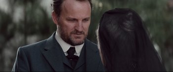 Movie still from “Winchester” (2018), directed by Michael Spierig – A man wearing a suit and tie talking to a woman wearing a veil; Close Up shot, Over the shoulder angle