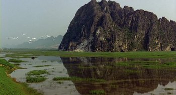 Movie still from “Winged Migration” (2001), directed by Jacques Cluzaud – A large mountain is reflected in the water; Extreme Wide shot, High angle