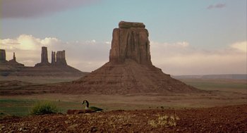 Movie still from “Winged Migration” (2001), directed by Jacques Cluzaud – A horse is standing in the middle of the desert; Extreme Wide shot, Low angle