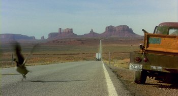 Movie still from “Winged Migration” (2001), directed by Jacques Cluzaud – A truck driving down a road in the middle of the desert; Extreme Wide shot, Low angle