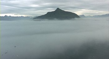 Movie still from “Winged Migration” (2001), directed by Jacques Cluzaud – A view of a mountain in the middle of the clouds; Extreme Wide shot, High angle