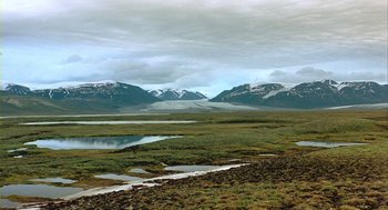 Movie still from “Winged Migration” (2001), directed by Jacques Cluzaud – A view of a mountain range with a lake in the foreground; Extreme Wide shot, High angle