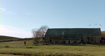 Movie still from “Winged Migration” (2001), directed by Jacques Cluzaud – An old barn with a person standing in front of it in a field; Extreme Wide shot, Low angle