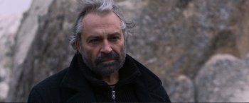 Movie still from “Winter Sleep” (2014), directed by Nuri Bilge Ceylan – An older man with a gray beard is posing for a picture; Close Up shot, Over the shoulder angle