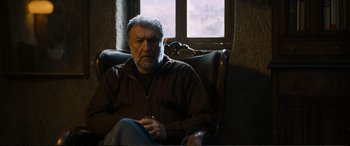 Movie still from “Winter Sleep” (2014), directed by Nuri Bilge Ceylan – An older man sitting in a chair in front of a window; Medium shot, Low angle