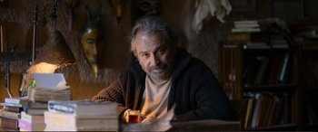 An older man sitting at a table with a glass of wine