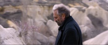 Movie still from “Winter Sleep” (2014), directed by Nuri Bilge Ceylan – An older man is looking down at the ground in front of him; Close Up shot, Over the shoulder angle