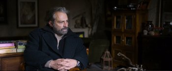 Movie still from “Winter Sleep” (2014), directed by Nuri Bilge Ceylan – A man sitting in a chair with his hands crossed; Medium shot, Low angle