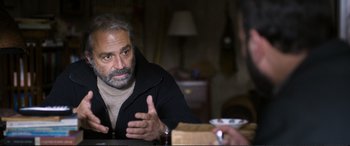 Movie still from “Winter Sleep” (2014), directed by Nuri Bilge Ceylan – A man sitting in front of a table talking to another man; Medium shot, Over the shoulder angle