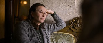 Movie still from “Winter Sleep” (2014), directed by Nuri Bilge Ceylan – A woman sitting on top of a chair next to a wall; Medium shot, High angle