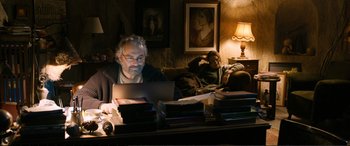 Movie still from “Winter Sleep” (2014), directed by Nuri Bilge Ceylan – A man sitting on a couch using a computer; Medium shot, Over the shoulder angle