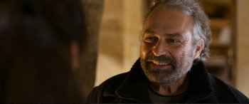 Movie still from “Winter Sleep” (2014), directed by Nuri Bilge Ceylan – An older man with grey hair and beard smiling; Close Up shot, Over the shoulder angle
