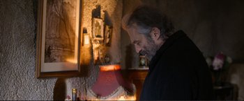 Movie still from “Winter Sleep” (2014), directed by Nuri Bilge Ceylan – A man standing in front of a lamp in a room; Medium shot, Over the shoulder angle