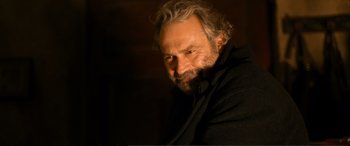 Movie still from “Winter Sleep” (2014), directed by Nuri Bilge Ceylan – A man with a beard is sitting in a dark room; Close Up shot, Over the shoulder angle