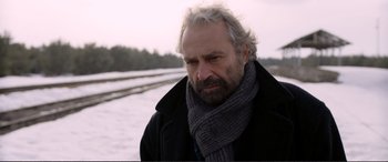Movie still from “Winter Sleep” (2014), directed by Nuri Bilge Ceylan – An older man wearing a black coat and a gray scarf; Close Up shot, Over the shoulder angle