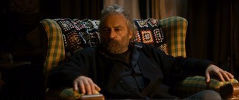 Movie still from “Winter Sleep” (2014), directed by Nuri Bilge Ceylan – An older man sitting in a chair holding a book; Medium shot, High angle