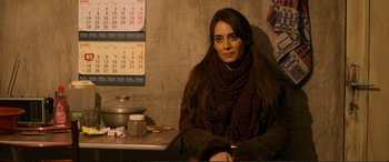 Movie still from “Winter Sleep” (2014), directed by Nuri Bilge Ceylan – A woman sitting at a table with a cup of coffee; Medium shot, Over the shoulder angle