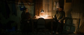 Movie still from “Winter Sleep” (2014), directed by Nuri Bilge Ceylan – Two people sitting at a wooden table in a dark room; Wide shot, High angle