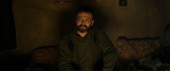 Movie still from “Winter Sleep” (2014), directed by Nuri Bilge Ceylan – A man with a goatee sitting in a dark room; Medium shot, Low angle