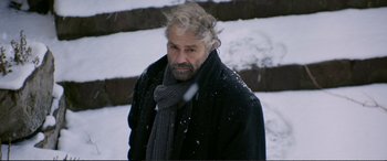 Movie still from “Winter Sleep” (2014), directed by Nuri Bilge Ceylan – A man in a black coat and a gray scarf; Close Up shot, Over the shoulder angle