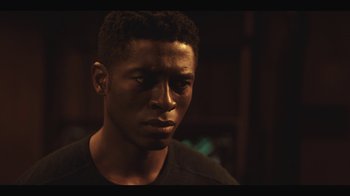 Movie still from “Another Life” (2019), created by Aaron Martin – A person wearing a black t - shirt; Close Up shot, Over the shoulder angle
