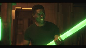 Movie still from “Another Life” (2019), created by Aaron Martin – A man is holding a glowing stick in his hand; Medium shot, Over the shoulder angle