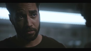 Movie still from “Another Life” (2019), created by Aaron Martin – A person with a beard looking at the camera; Close Up shot, Over the shoulder angle
