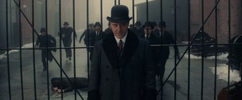 Movie still from “Winter's Tale” (2014), directed by Akiva Goldsman – A man wearing a hat and a suit; Medium shot, Low angle