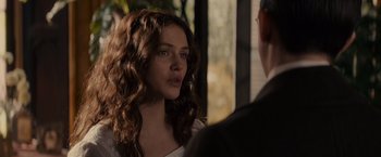 Movie still from “Winter's Tale” (2014), directed by Akiva Goldsman – A beautiful young woman with long brown curly hair standing next to a man; Close Up shot, Over the shoulder angle