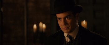 Movie still from “Winter's Tale” (2014), directed by Akiva Goldsman – A man wearing a black hat and a black suit; Close Up shot, Over the shoulder angle