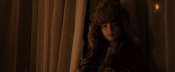 Movie still from “Winter's Tale” (2014), directed by Akiva Goldsman – A young girl wearing a fur hat looking out of a window; Close Up shot, Low angle